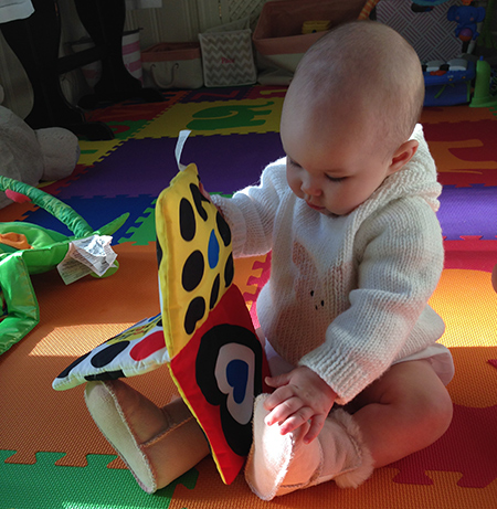 At seven months, Pace is sitting up on her own and holding age-appropriate books like this cloth one